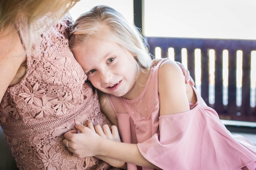 Young girl cuddling up to mother - Australian Stock Image