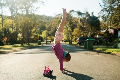 Young girl doing a handstand on the road - Australian Stock Image
