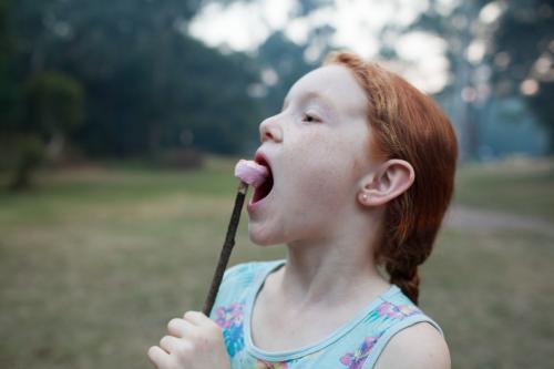 Young girl eating a toasted marshmallow - Australian Stock Image