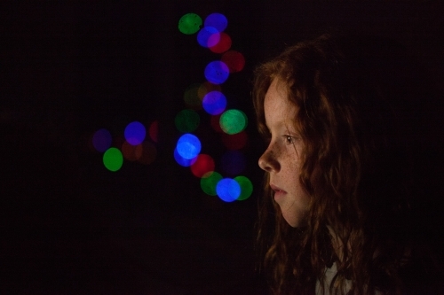 Young girl in low light with coloured lights - Australian Stock Image