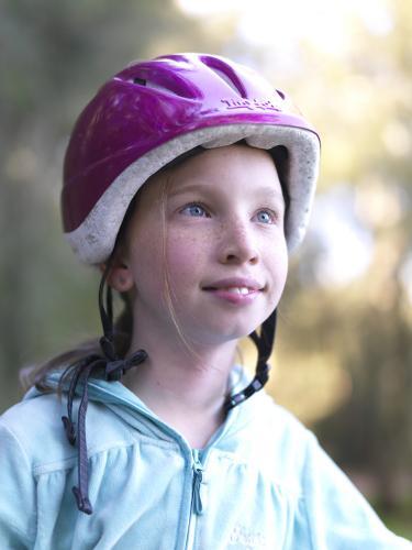 Young girl in purple helmet preparing to go bike riding