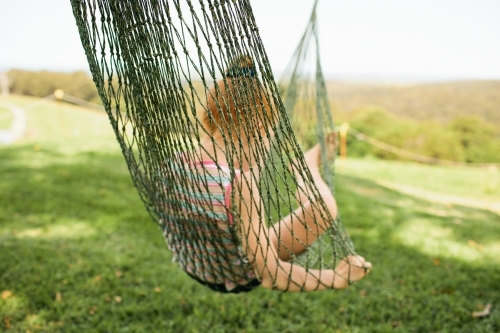 Young girl laying in a green hammock - Australian Stock Image