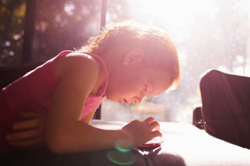 Young girl looking at a device - Australian Stock Image