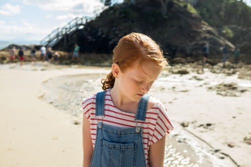 Young girl looking down at the beach - Australian Stock Image