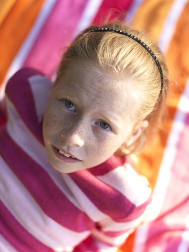 Young girl lying on stripy towel - Australian Stock Image