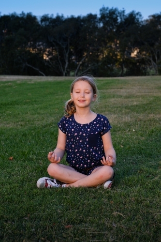 Young girl meditating in the park - Australian Stock Image