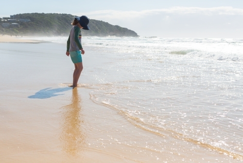 Young girl on a beach looking at the sea - Australian Stock Image