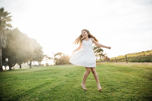 Young girl playing in a field in the sunshine - Australian Stock Image