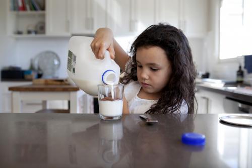 Young girl pouring milk into a glass