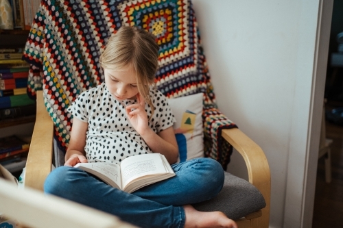 Young girl reading a book at home