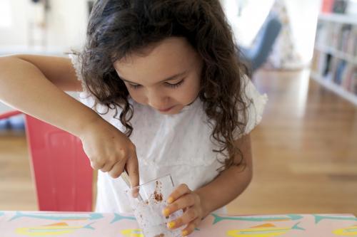 Young girl scooping chocolate from a glass - Australian Stock Image