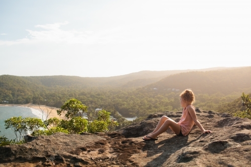 Young girl sitting on a rock looking at the view