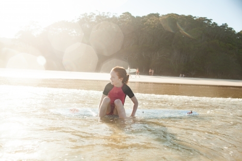 Young girl sitting on a surfboard at the beach