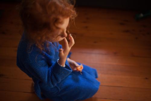 Young girl sitting on the floor eating a mandarin
