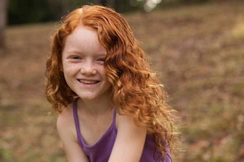 Young girl smiling in an open field - Australian Stock Image