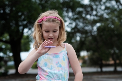 Young girl smiling playing with fidget spinner toy - Australian Stock Image