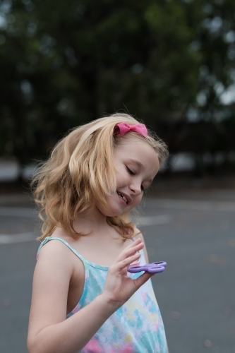 Young girl smiling playing with fidget spinner toy - Australian Stock Image