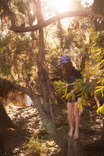 Young girl standing among trees in afternoon light