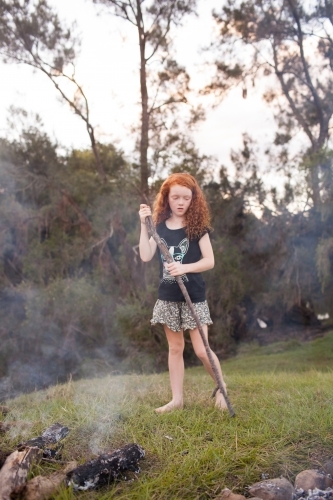 Young girl standing beside a campfire - Australian Stock Image