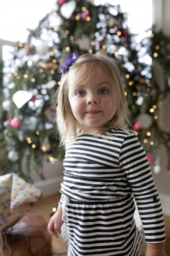 Young girl standing in front of Christmas tree