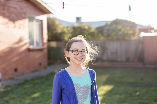 Young girl standing under washing line smiling