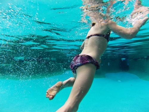 Young girl swimming underwater at a pool - Australian Stock Image