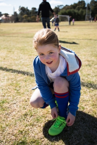 Young girl tying her shoelace at soccer - Australian Stock Image