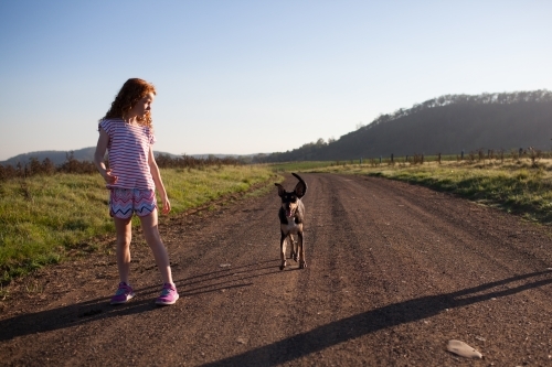 Young girl walking her dog on a dirt road - Australian Stock Image