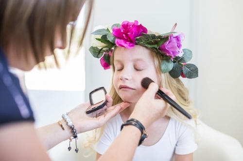 Young girl wearing flower crown getting makeup done