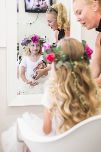 Young girl with flower crown sitting in hairdressing chair - Australian Stock Image