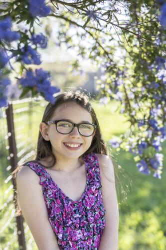 Young girl with glasses under a jacaranda tree - Australian Stock Image