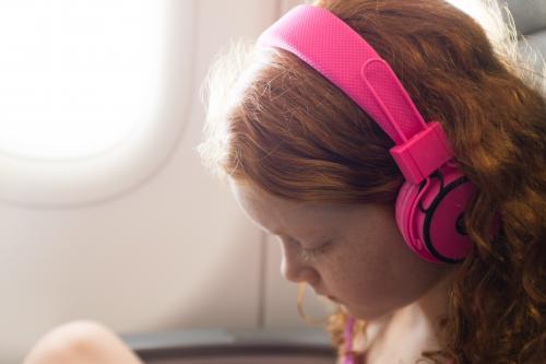 Young girl with headphones on a passenger plane - Australian Stock Image