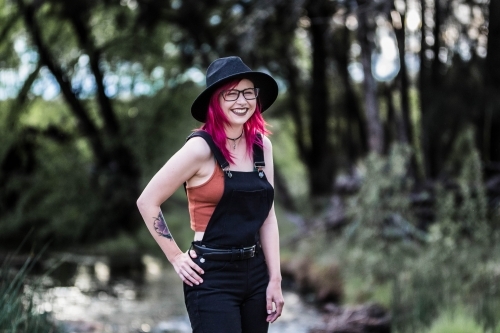 Young girl with pink hair standing with hand on hip laughing - Australian Stock Image