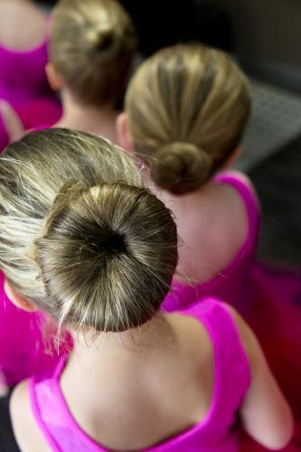 Young girls dressed in pink and wearing buns ready to perform at a ballet concert - Australian Stock Image