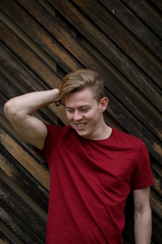 Young happy caucasian man modelling in front of a wooden panelled background - Australian Stock Image