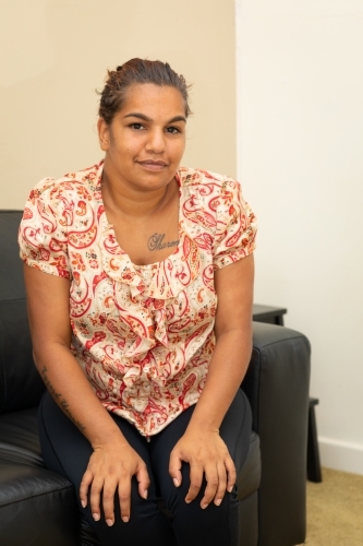 young indigenous woman sitting forward on sofa with arm on knees