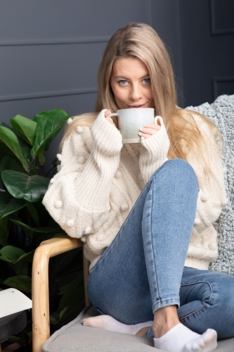 Young lady relaxing drinking hot chocolate or coffee on a cold winters day - Australian Stock Image