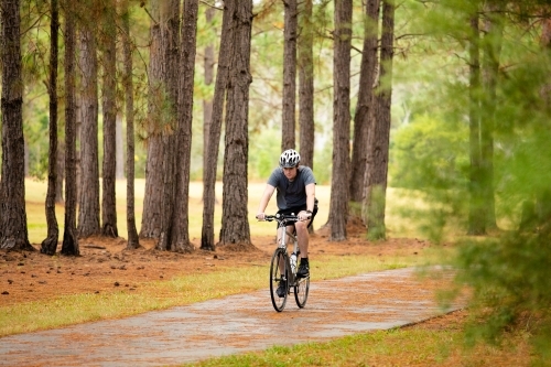 Young male cycling along a parkland bike path - Australian Stock Image