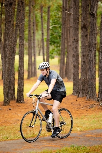 Young male cycling along a parkland bike path - Australian Stock Image