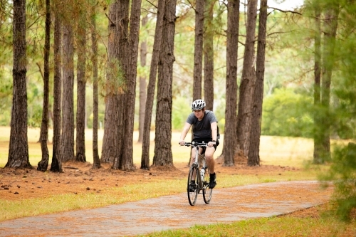 Young male cycling along a parkland bike path - Australian Stock Image