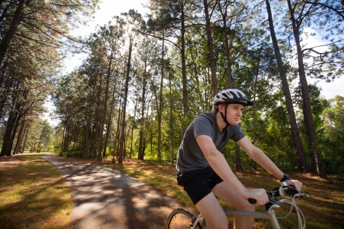 Young male cycling along a parkland bike path - Australian Stock Image