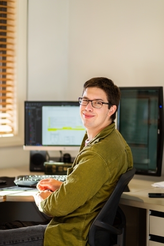 Young male uni student studying on computer at desk - Australian Stock Image