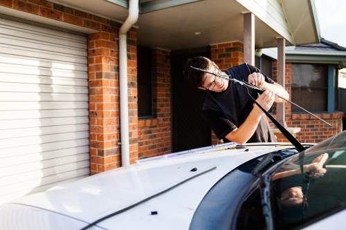 Young man fixing his cars windscreen wipers - Australian Stock Image
