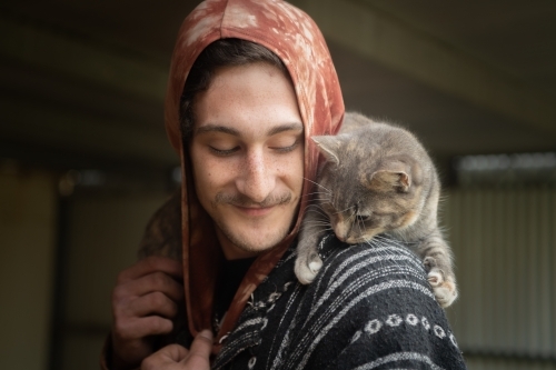 Young man with pet cat connecting. - Australian Stock Image