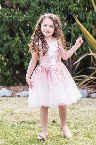 Young mixed race aboriginal caucasian girl with curly hair standing in garden smiling - Australian Stock Image