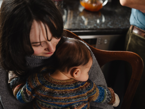 Young mother holding baby dressed in striped sweater - Australian Stock Image