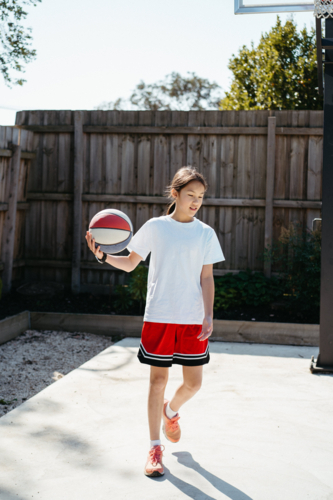 Young pre-teen girl playing basketball in the backyard - Australian Stock Image