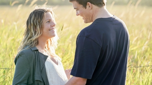 Young pregnant couple looking at each other, half shot - Australian Stock Image