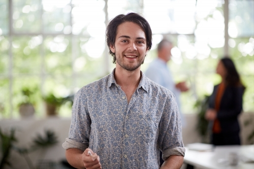 Young professional man standing in an open plan office - Australian Stock Image