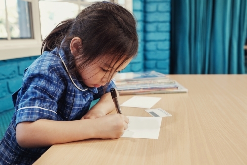 Young student girl writing in libary - Australian Stock Image